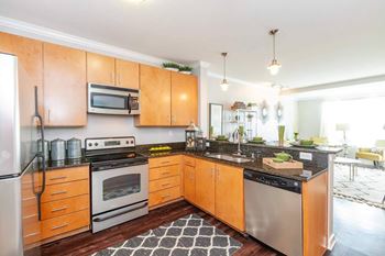 A kitchen with wooden cabinets and a black and white checkered floor at 45 Madison Apartments, Kansas City, 64111